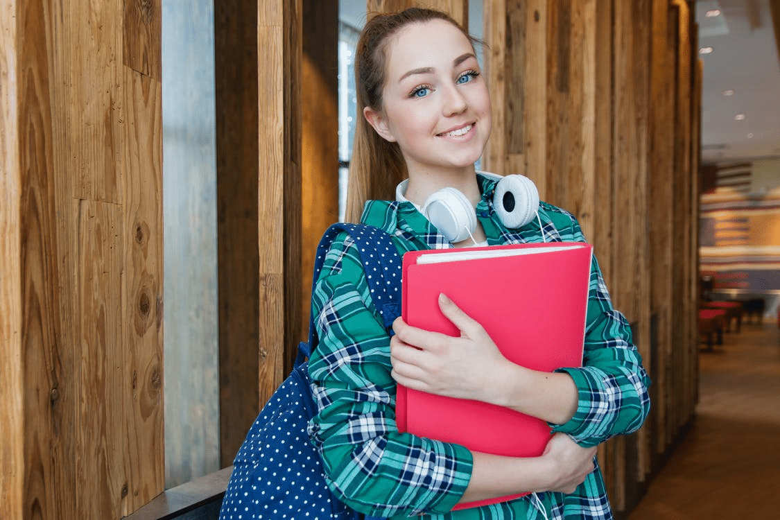 an A Level student smiling and holding books