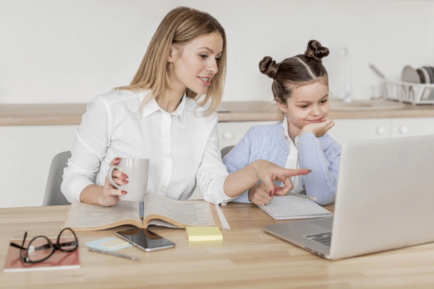 a-young-girl-attending-online-school-as-her-mother-watches-on