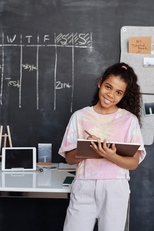 a student writing in a notebook with a blackboard in the background