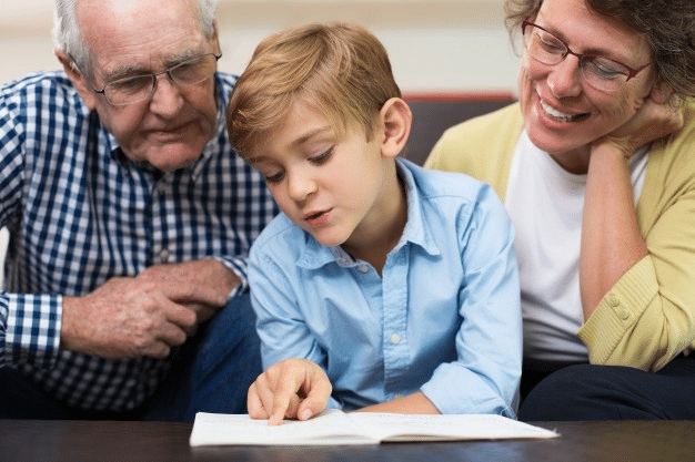 a child confidently reading a text out loud to his grandparents