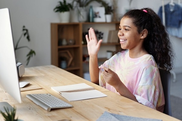 a child waving to her peers during an online class