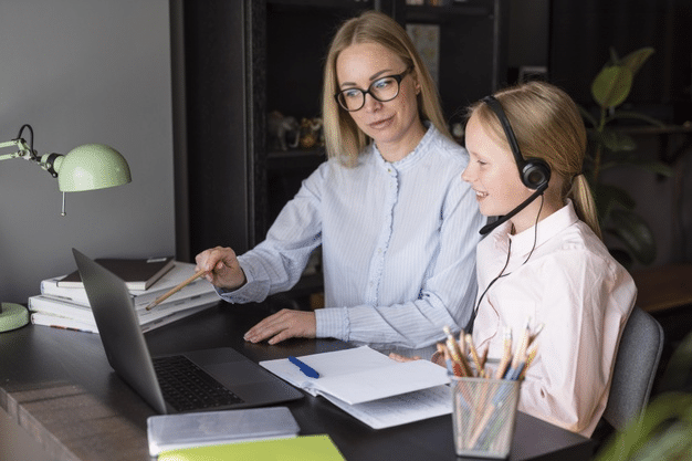 a girl attending online school as her mother provides guidance