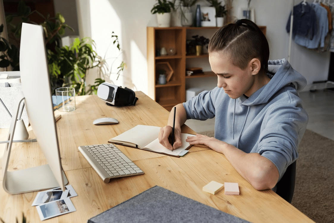 a student taking notes during his online class