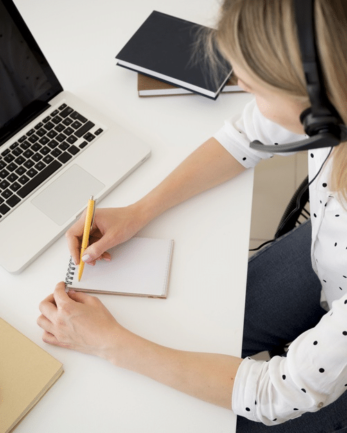 a young girl taking notes during an online class