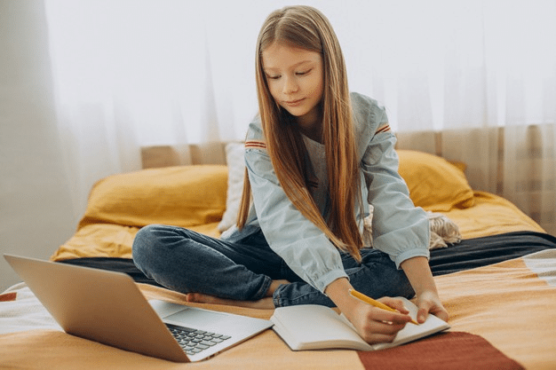 a young girl taking notes during online clas