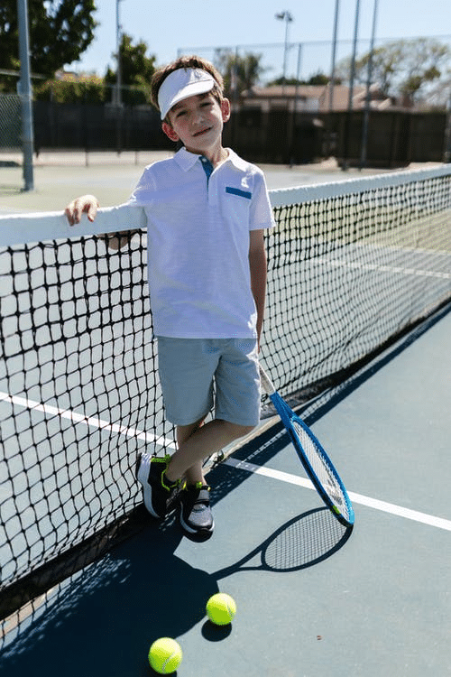 young boy standing on a tennis court