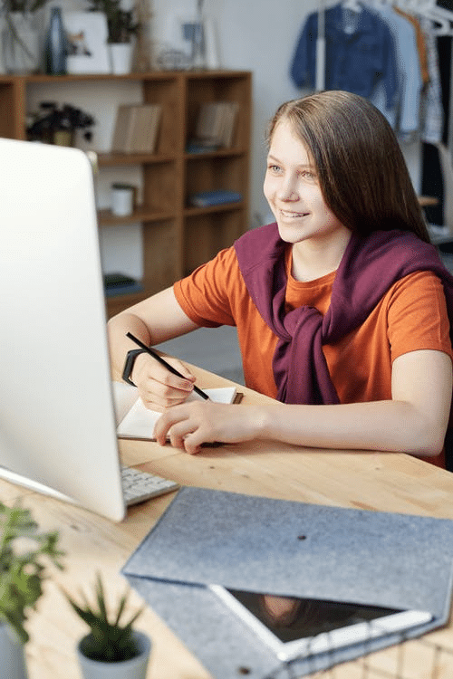 a girl taking notes during her first online class in Teesside