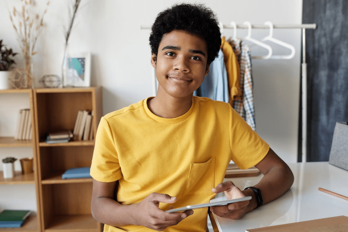 a student smiling at the camera as he revises for online school