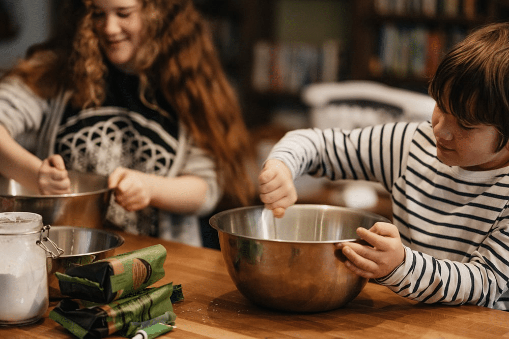 a teenage girl and young boy cooking in the kitchen