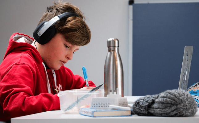 male student doing classwork and eating lunch during an online class